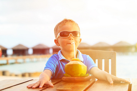 小男孩喝椰子鸡尾酒热带海滩上