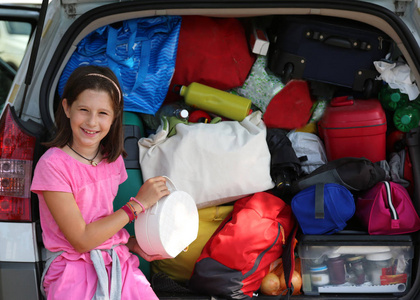 小女孩加载在她的汽车行李箱包