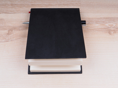 黑色笔记本和一支钢笔在一个木制的背景