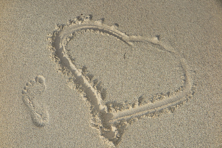 在沙子中绘制的心。海滩背景。顶视图