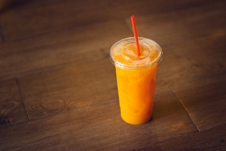 一杯橙汁加冰在木地板上照片