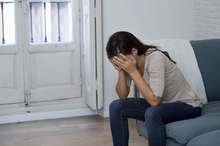 西班牙裔女人在哭躺在家里坐在沙发上哭泣的拉丁女人担心痛苦抑郁感到