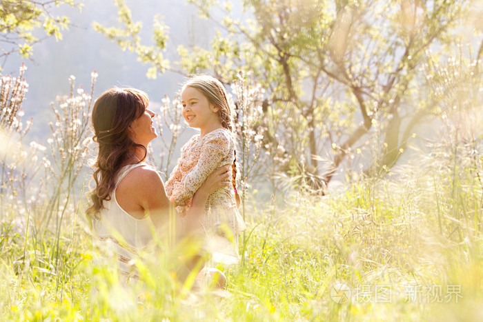 母亲和女儿拥抱在春天的田野里