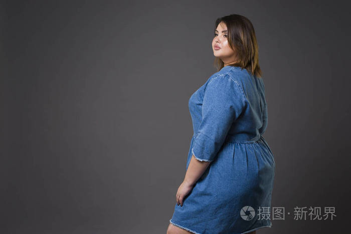 再加上大小时装模特在随意的牛仔衣服胖女人在灰色的背景下超重女性的