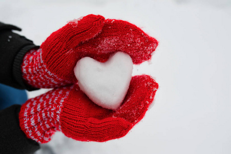 红女手套捧着一个白色的心脏从雪