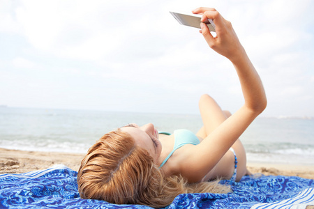 在海滩上使用智能手机的女人