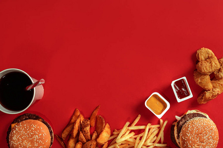 汉堡和薯条。汉堡包和炸薯条红纸框中。红色背景上的快餐食品