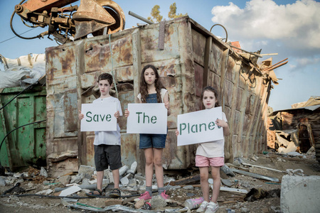 拯救地球。年幼的孩子，手拿著站在一个巨大的垃圾场的标语