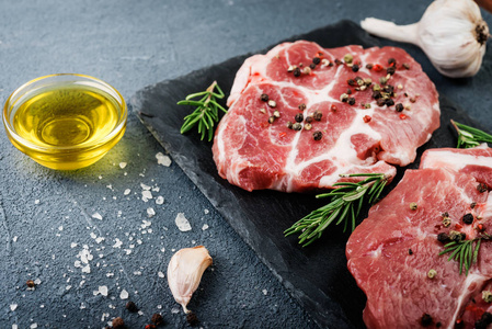 在深色背景下用迷迭香和香料的生肉牛排