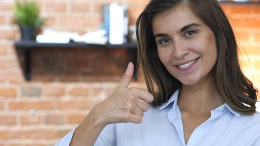 赞赏手指竖起大拇指,表示赞赏的年轻漂亮的女孩照片