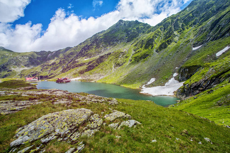 高山湖泊。岩石间湖。在岸上的酒店。前景中的岩石。人类发展报告 