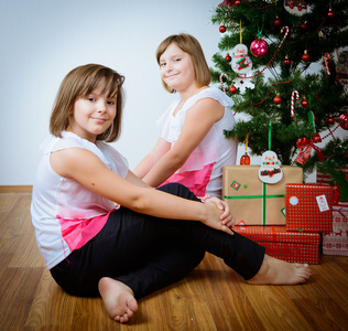 两个女孩在与礼物的圣诞树前