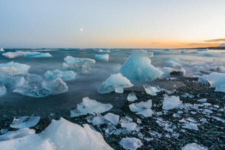 在日落时在 Jokulsarlon，冰岛的黑色沙滩上的冰山