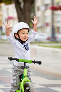 小男孩孩子戴头盔骑自行车在城市公园。性格开朗的孩子户外