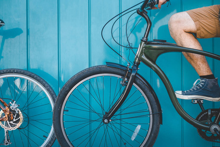 坐着一辆自行车沿蓝色墙背景日常生活方式城市休息的概念变得面目全非年轻骑自行车的人
