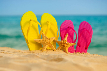 黄色 粉色凉鞋海星站在背景下的海砂