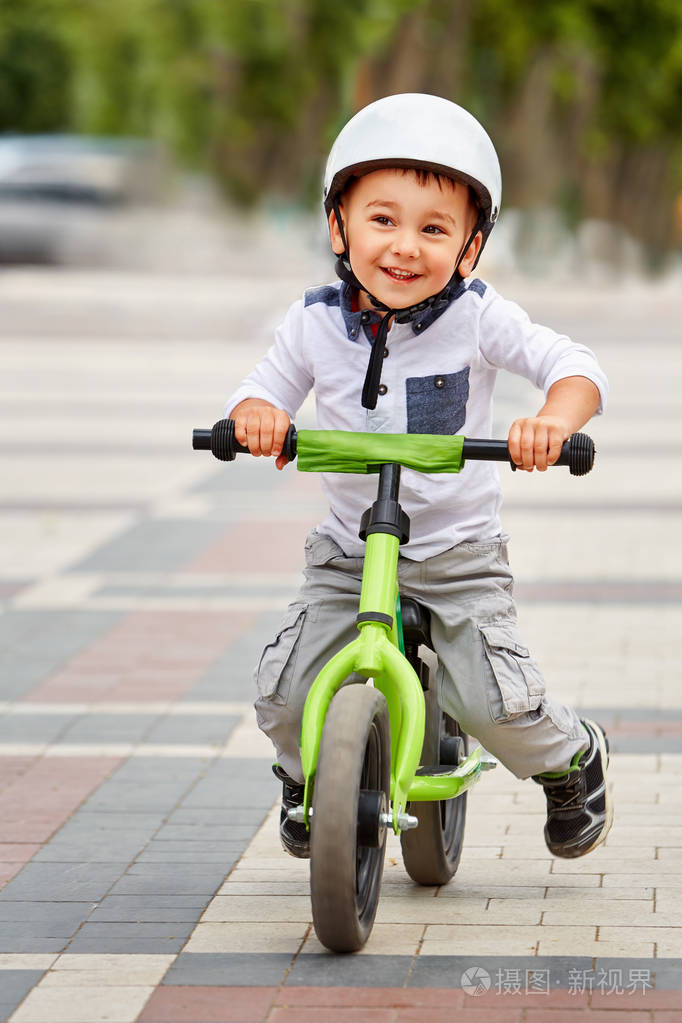 小男孩孩子戴头盔骑自行车在城市公园.性格开朗的孩子户外