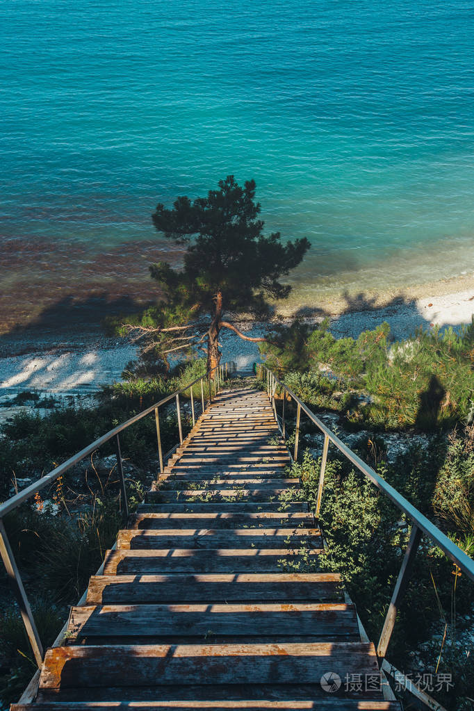 木制楼梯通往海岸，在早晨日出旅游目的地度假概念