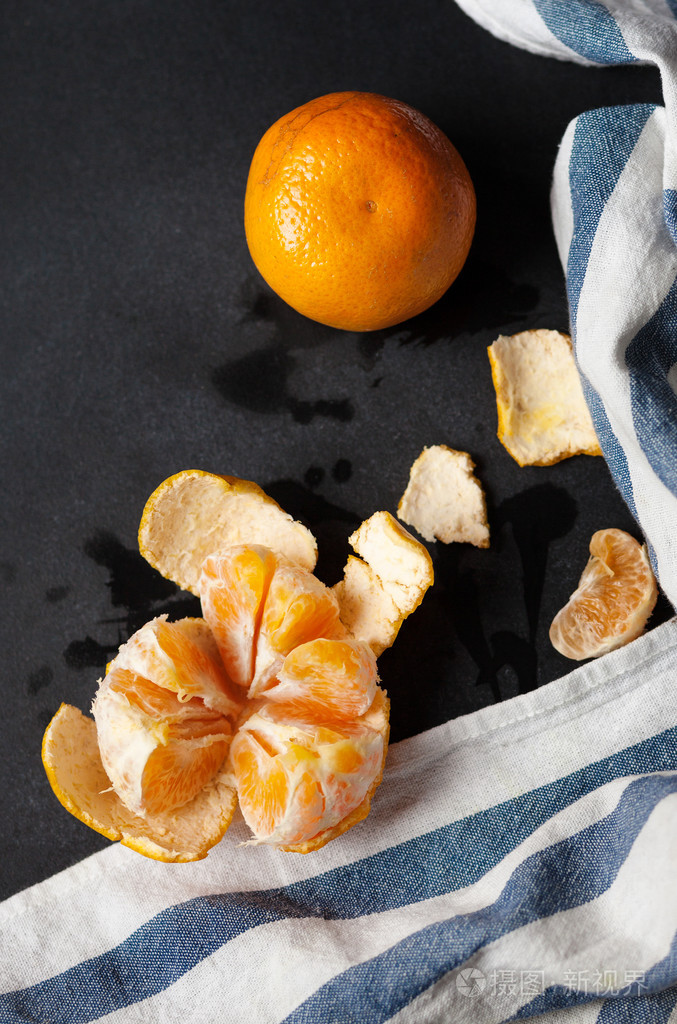 两个橘子躺在黑色的桌子上用条纹亚麻毛巾