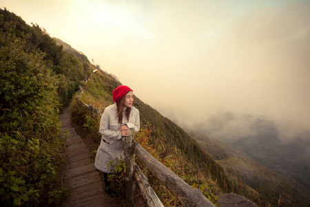 年轻的女子在峭壁上，俯瞰群山