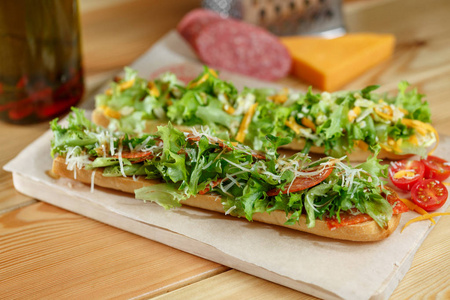 健康新鲜的硬皮法式面包潜水艇三明治与萨拉米香肠 奶酪和芝麻菜。选择性的焦点