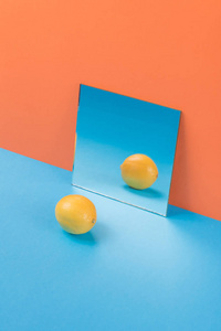 孤立在橙色背景的蓝色桌子上柠檬