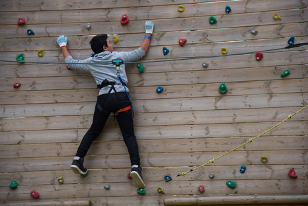 小男孩爬上爬墙行走在洋红色背心, 牛仔裤和运动鞋的女人.