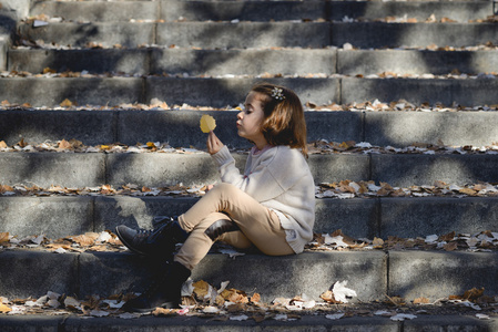 在秋天在城市公园里玩耍的小女孩