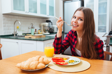 可爱微笑的女人在厨房上早饭吃煎的鸡蛋