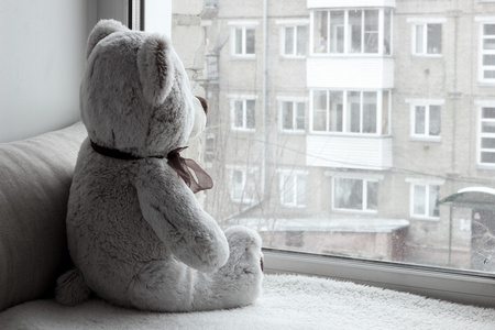 玩具熊坐在窗台上看着窗外