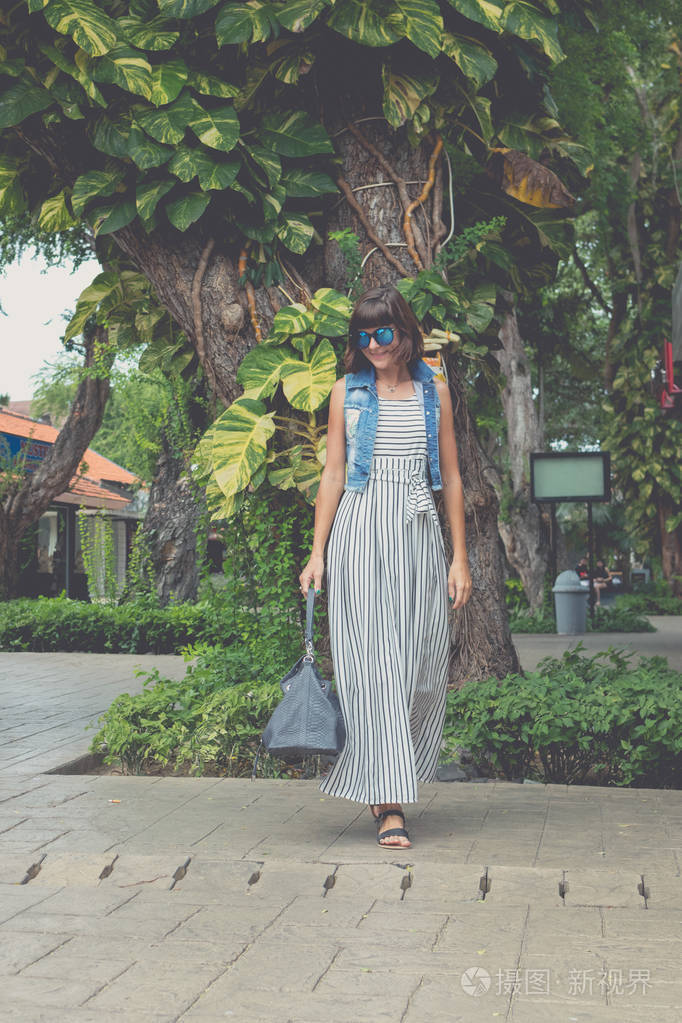 太阳镜与时尚蛇皮python包走在大街上的女人印度尼西亚巴厘岛