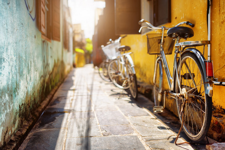 自行车停在阳光明媚的街道上旧房子的黄墙附近