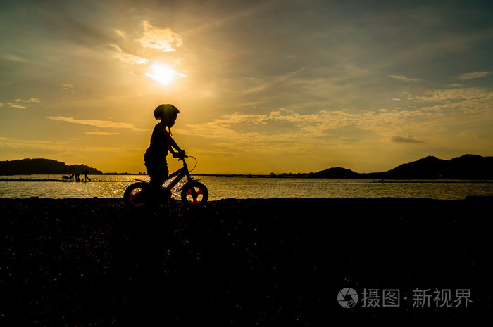 儿童骑自行车在夕阳中的剪影