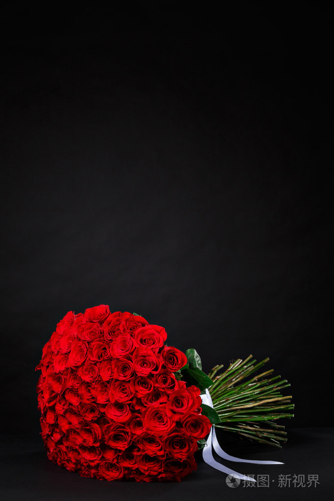 一束101朵红玫瑰放在黑色工作室b上的标志上