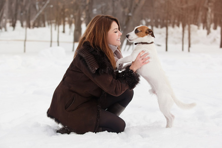 年轻的红发女子户外与可爱的小狗杰克罗素梗犬，冬季