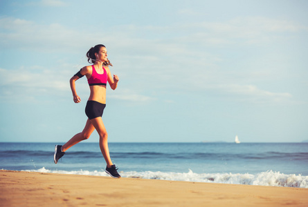 体育健身女人在日落时分在沙滩上跑