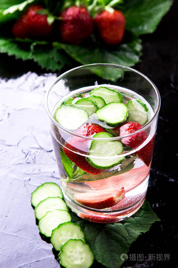 黄瓜和草莓排毒水在黑色背景上的玻璃.背光.饮食