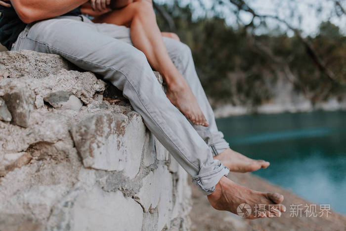 男人和女人的腿交错坐在一堵墙在性质上