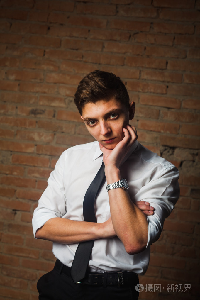 时尚帅气年轻男模白色砖墙前摆姿势