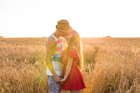 年轻爱情侣接吻在阳光中的字段