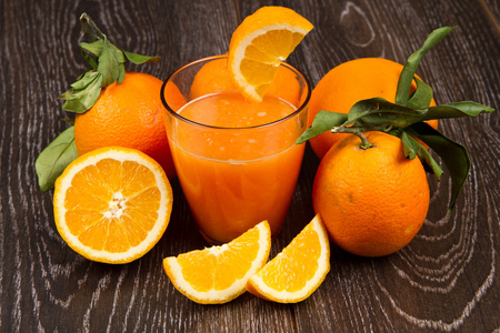 杯鲜桔子汁和橙子木制背景上