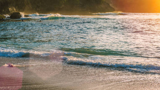 当地的孩子们冲浪波在夕阳的光线，美丽水晶湾，Nusa Penida 巴厘岛