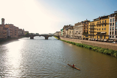 阿尔诺河上的划船 桥梁和建筑物在日落时概述。在佛罗伦萨市