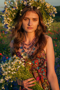 女孩用的鲜花花环。脸上的美丽的乌克兰女孩在夏天在性质上花圈