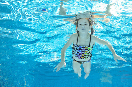 儿童游泳在游泳池水下，快乐积极的女孩已经在水里，孩子运动家庭度假的乐趣