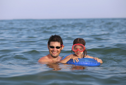 年轻爸爸和他的女儿戴着面具在夏天