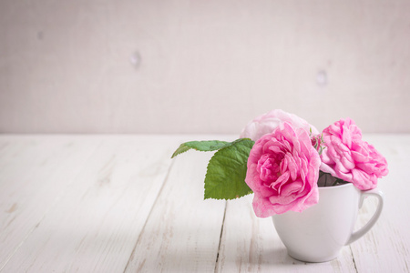 白色的木制背景上的粉红色玫瑰花茶