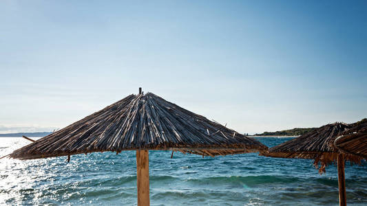 稻草伞在海边的海滩上。热带背景