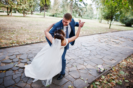 神话般的年轻新婚夫妇摆在阳光明媚的大街上的公园