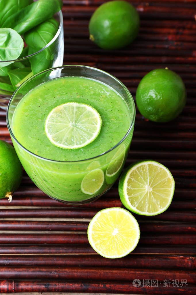 罗勒和桌上的酸橙绿色健康果汁玻璃关闭